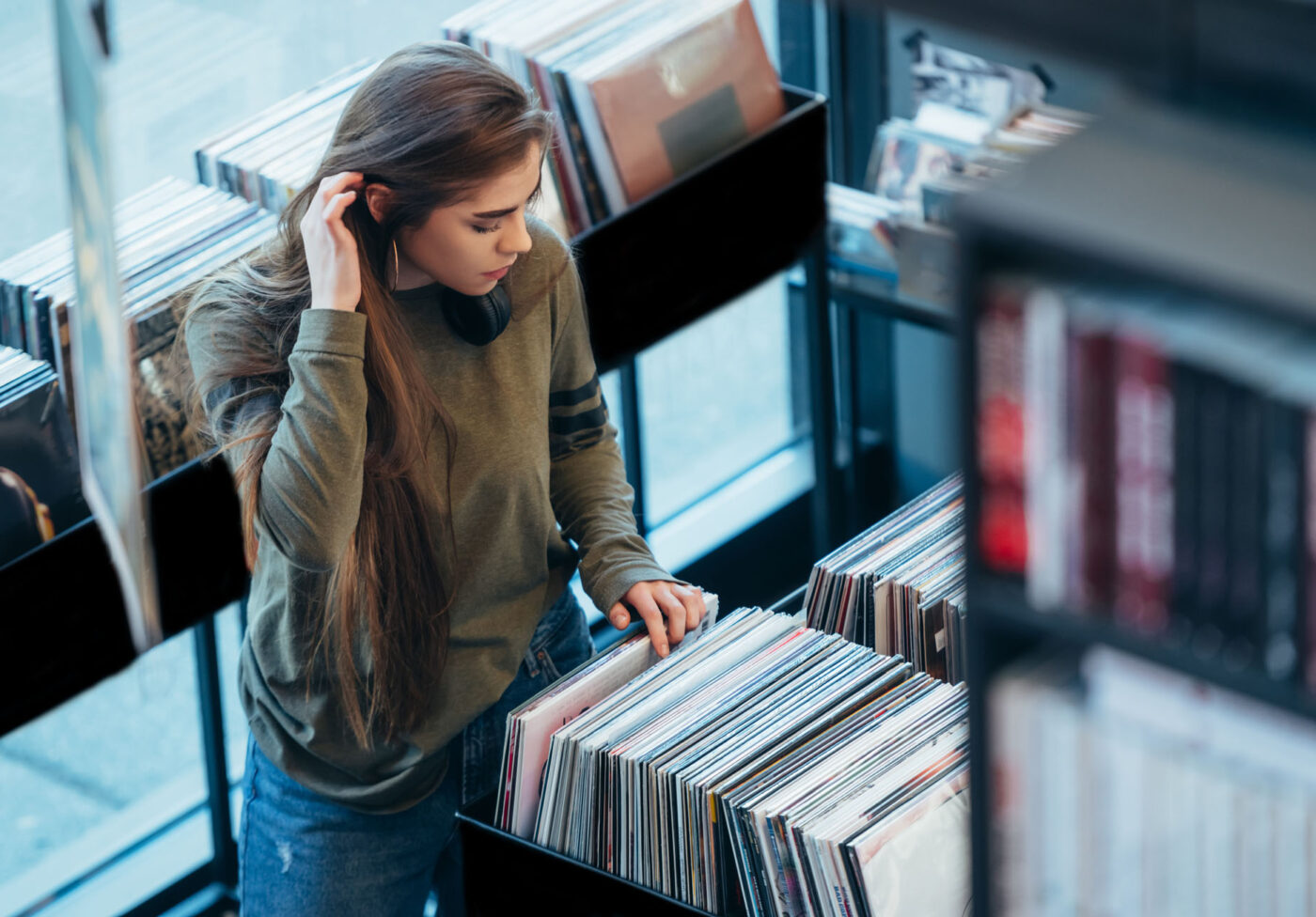 Woman choosing vinyl record in music record shop Gorgeous young woman looking for vinyl records in a vintage store. Vintage and retro style.